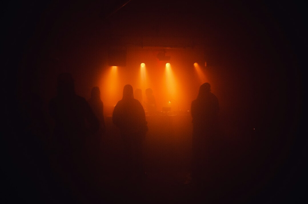 Silhouetted audience at an evening concert with warm stage light